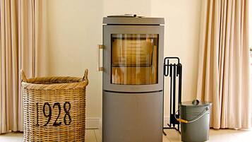 A room with a modern heating unit, a wicker basket with the number 1928, and a metal bucket.