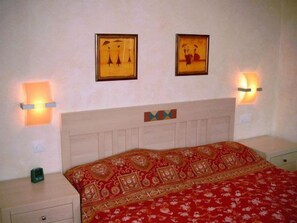 A hotel room with a bed, two wall-mounted lamps, and two framed pictures on the wall. - Right on the sandy Baltic Sea beach with a view of the sea!, Wi-Fi, washing machine, accommodates up to 3 people (Glowe)
