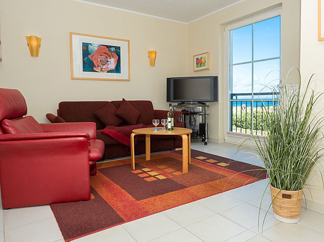 A living room with a red sofa, a wooden coffee table, a TV, and a large window with a view.