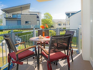 Une terrasse extérieure avec une table et des chaises, un verre et un arrangement floral.