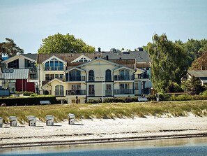 A coastal hotel with multiple buildings, a sandy beach, and a calm water body. - Right on the sandy Baltic Sea beach with a view of the sea!, Wi-Fi, washing machine, accommodates up to 3 people (Glowe)
