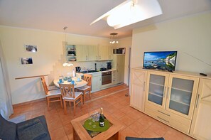 A compact living space with a dining area, kitchenette, and a television. - Just 50 meters from the sandy Baltic Sea beach, Wi-Fi, accommodates up to 4 people, with a covered patio (Glowe)