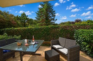 An outdoor patio with wicker furniture, a glass table, and a bottle of wine. - Just 50 meters from the sandy Baltic Sea beach, Wi-Fi, washer/dryer, sleeps up to 4 people, with a terrace (Glowe)