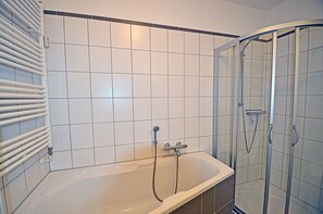 A bathroom with a bathtub, shower, and a glass-enclosed shower stall. - Just 50 meters from the sandy Baltic Sea beach, Wi-Fi, washer/dryer, sleeps up to 4 people, with a terrace (Glowe)
