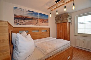 A bedroom with a wooden bed, a large window, and a wall-mounted light fixture. - Just 50 meters from the sandy Baltic Sea beach, Wi-Fi, washer/dryer, sleeps up to 4 people, with a terrace (Glowe)