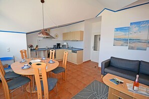 Kompakti oleskelutila, jossa on ruokailualue, pieni keittiö ja sohva.