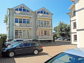 A multi-story residential building with balconies, parked cars, and a clear sky. - Just 35 meters from the sandy Baltic Sea beach, Wi-Fi, 2 bedrooms, sleeps up to 5 people, with a balcony (Glowe)