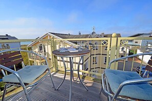 A balcony with a metal table and two chairs, overlooking a residential area with buildings and a clear sky. - Just 35 meters from the sandy Baltic Sea beach, Wi-Fi, 2 bedrooms, sleeps up to 5 people, with a balcony (Glowe)