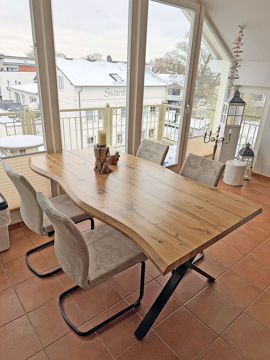 Ein Holztisch mit gewobenen Stühlen in einem Raum mit großen Fenstern.
