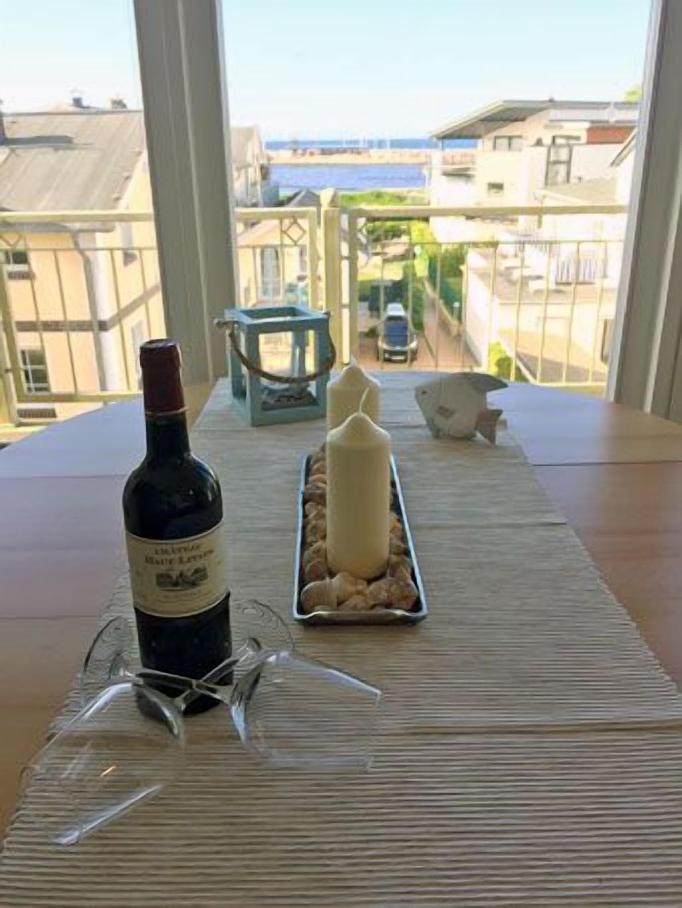 Una mesa con una botella de vino, copas, una vela y una bandeja de frutos secos.