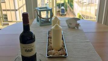 Una mesa con una botella de vino, copas, una vela y una bandeja de frutos secos.