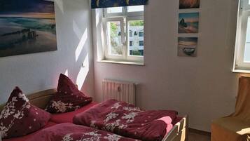 A bedroom with two beds, a radiator, and a window with curtains.