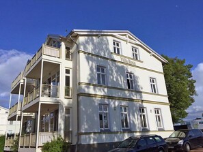Un immeuble de deux étages doté de balcons, une enseigne indiquant « Villa Rosa », et une voiture garée devant.