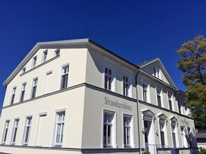 Ein Gebäude im klassischen Stil, mit einer symmetrischen Fassade, gleichmäßig verteilten Fenstern und einem zentralen Eingang.
