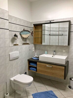 Casa de banho com sanita, lavatório e espelho.