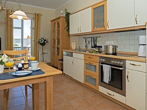 Cozinha com mesa de jantar, armários, máquina de café e janela com cortinas.