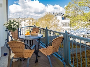 Ein Balkon mit Korbstühlen, einem Tisch mit Obstschale und einem Blumentopf.
