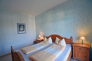 A double bed with a wooden headboard, two bedside tables with lamps, a framed picture on the wall, and a light blue textured wall. - Just 100 meters from the sandy Baltic Sea beach, Wi-Fi, 1 bedroom, sleeps up to 4, with a balcony (Glowe)