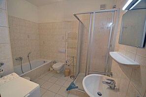 Une salle de bain équipée d’une baignoire, de toilettes, d’un lavabo et d’un espace douche.
