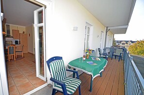 Un balcon avec une table, des chaises et une vue sur l’extérieur.