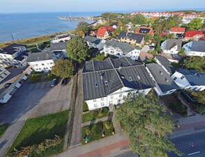 An aerial view of a residential area with houses, a paved road, and a body of water in the background. - Just 100 meters from the sandy Baltic Sea beach, Wi-Fi, 1 bedroom, sleeps up to 4, with a balcony (Glowe)
