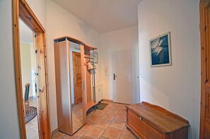 A hallway with a wooden bench, a door, a radiator, and a framed picture on the wall. - Just 100 meters from the sandy Baltic Sea beach, Wi-Fi, 1 bedroom, sleeps up to 4, with a balcony (Glowe)