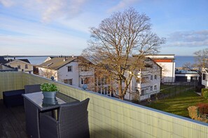 Ein Balkon mit Gartenmöbeln, Blick auf eine Wohngegend und ein Baum.