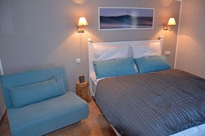 Ein Schlafzimmer mit einem Bett, zwei Wandlampen, einem blauen Sofa und einem Bild an der Wand.