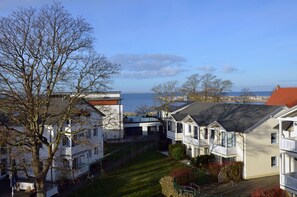 Ein Wohngebiet mit mehreren zweistöckigen Häusern, blauem Himmel und Blick auf das Meer.