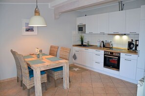 Eine kleine Küche mit weißen Schränken, einer Mikrowelle, einem Toaster und einem Backofen.