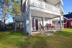 Ein zweistöckiges Haus mit überdachter Veranda, Sitzgelegenheiten im Freien und einer Garage.