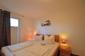 Ein Hotelzimmer mit einem Bett, zwei Nachttischen, einem Fenster mit Vorhängen und einer Wanddekoration.