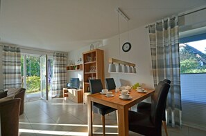 Un comedor con una mesa de madera, sillas y una estantería.