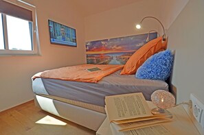Ein Schlafzimmer mit einem Bett, einem Gemälde, einer Lampe und einem Buch.