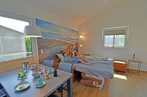 Una habitación con cama, una mesa con alimentos para el desayuno y un cuadro en la pared.