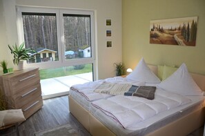 A bedroom with a bed, a dresser, a window, and a painting on the wall. - Only 800 meters from the sandy Baltic Sea beach, Wi-Fi available, balcony with patio furniture (Glowe)
