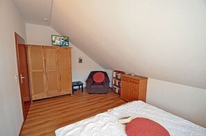 A bedroom with a bed, a wardrobe, a small table, a chair, and a bookshelf. - Just 250 meters from the sandy Baltic Sea beach, balcony with patio furniture and a beach umbrella (Glowe)