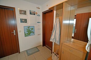 A room with wooden doors, a map on the wall, a towel hanging, and a mirror. - Just 250 meters from the sandy Baltic Sea beach, balcony with patio furniture and a beach umbrella (Glowe)