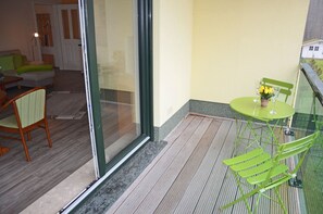 A balcony with a green table and chairs, a small potted plant, and a view of a house in the background. - Just 800 meters from the sandy Baltic Sea beach, Wi-Fi available, balcony with patio furniture (Glowe)
