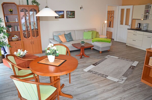 A living room with a sofa, a dining table with chairs, a cabinet with glass doors, and a kitchen area. - Just 800 meters from the sandy Baltic Sea beach, Wi-Fi available, balcony with patio furniture (Glowe)