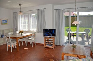 A living room with a television, dining table, chairs, and a view of the outdoors. - Only 500 meters from the sandy Baltic Sea beach, patio with patio furniture, Internet available (Glowe)