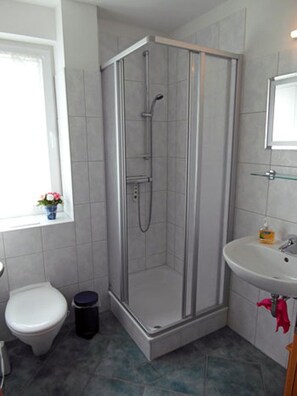 A bathroom with a shower, toilet, sink, and window. - Only 500 meters from the sandy Baltic Sea beach, balcony with patio furniture, internet available (Glowe)