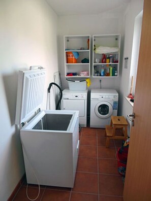 Un lavadero pequeño con lavadora, secadora y estantes para almacenamiento.