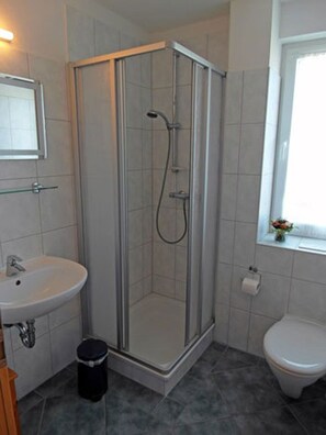A bathroom with a glass-enclosed shower, a sink, a toilet, and a window with a view. - Only 500 meters from the sandy Baltic Sea beach, balcony with patio furniture, Internet available (Glowe)