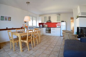 A modern kitchen with white cabinets, a red backsplash, and a dining area with wooden furniture. - 2nd floor, ocean view, high-end amenities, 25 m from the sandy beach (Baltic Sea) (Juliusruh)