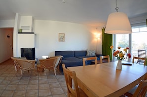 A living room with a sofa, chairs, a dining table, and a fireplace. - 2nd floor, ocean view, high-end amenities, 25 m from the sandy beach (Baltic Sea) (Juliusruh)
