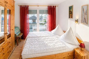Ein Schlafzimmer mit einem großen Bett, einem Holzschrank und Blick ins Freie.