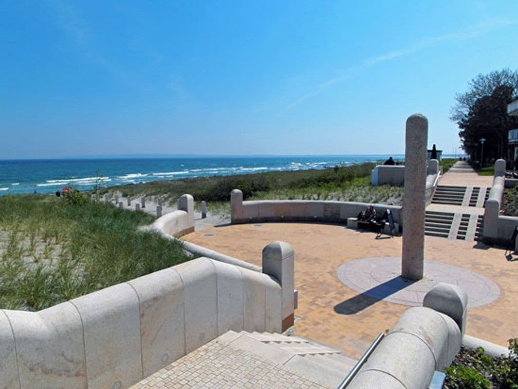 Eine Uferpromenade mit einem runden Sitzbereich, einem Weg zum Strand und Blick auf den Ozean.