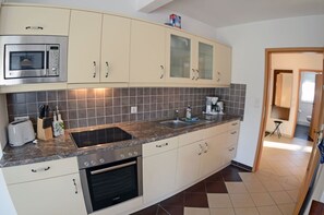 Cozinha equipada com micro-ondas, forno, pia e armários.