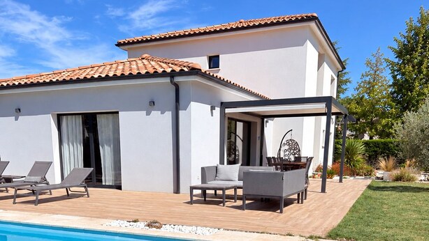 Ein modernes Haus mit Pool, Sitzgelegenheiten im Freien und einem Garten.